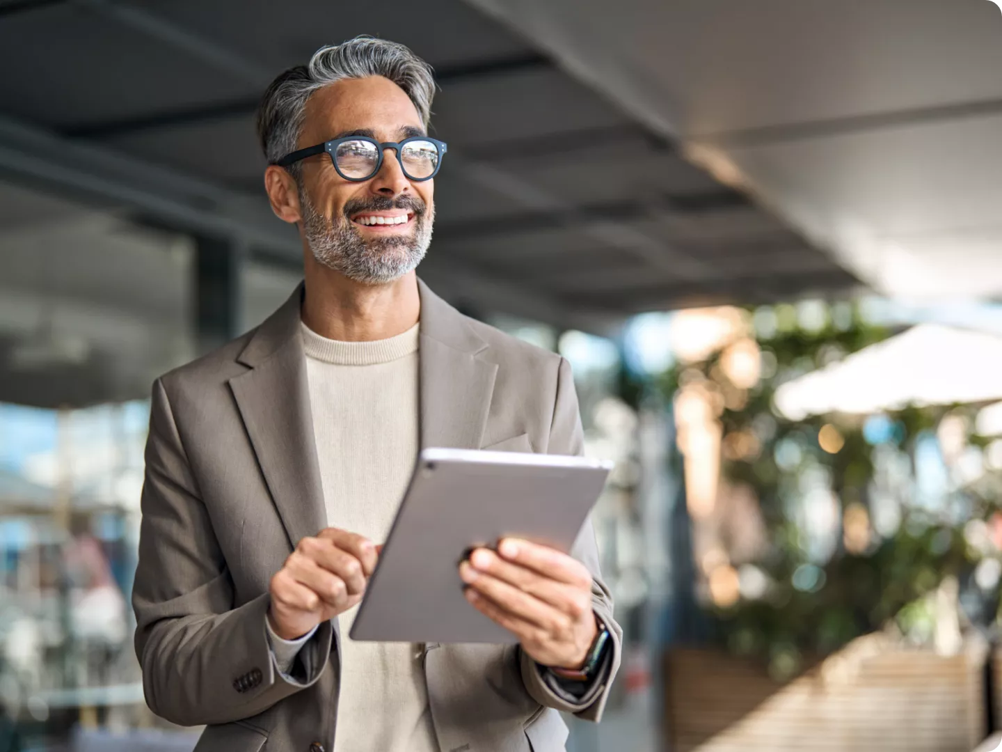 Smiling man in glasses holding a tablet.
