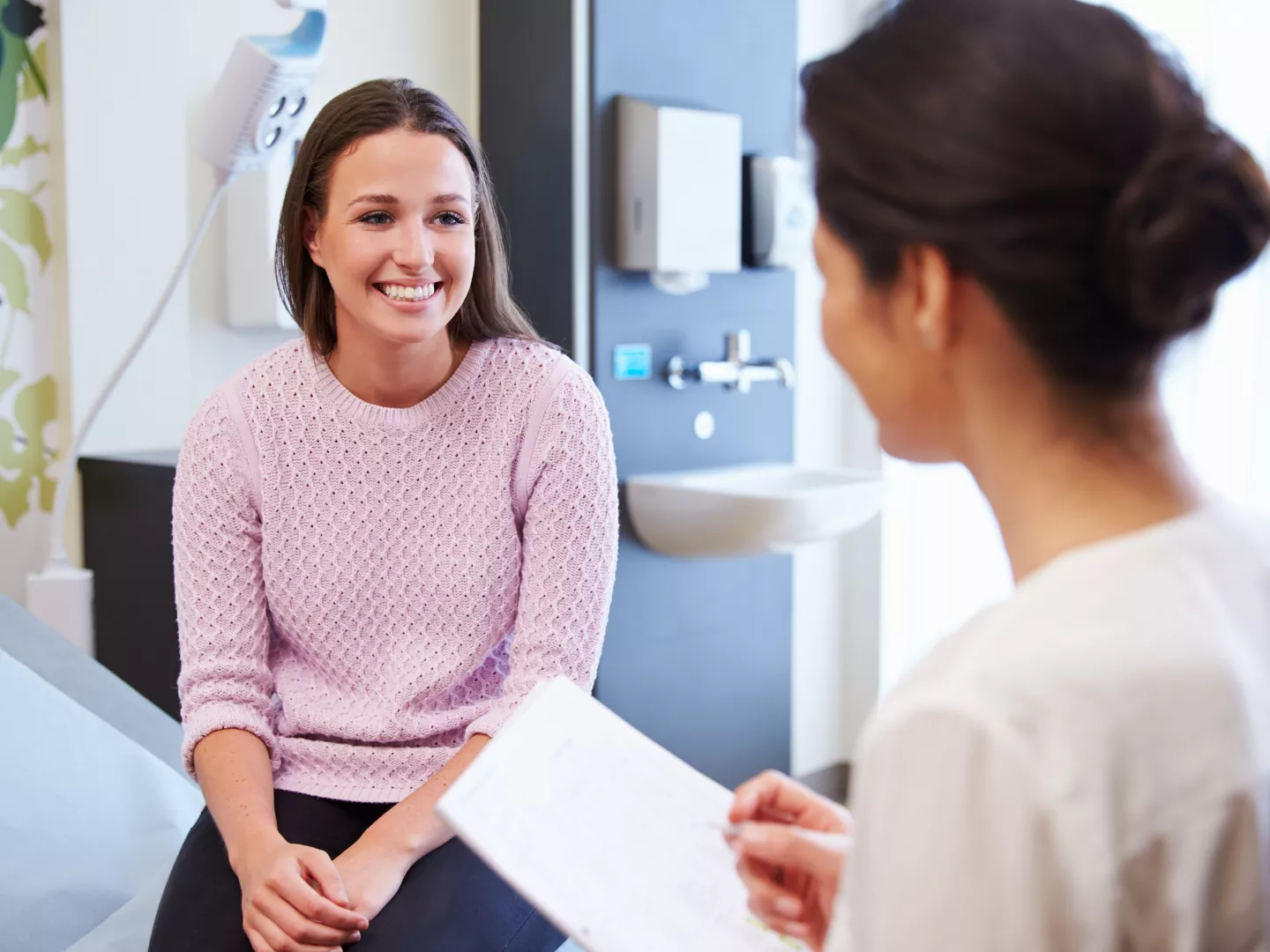A patient talking to a care worker in an exam room