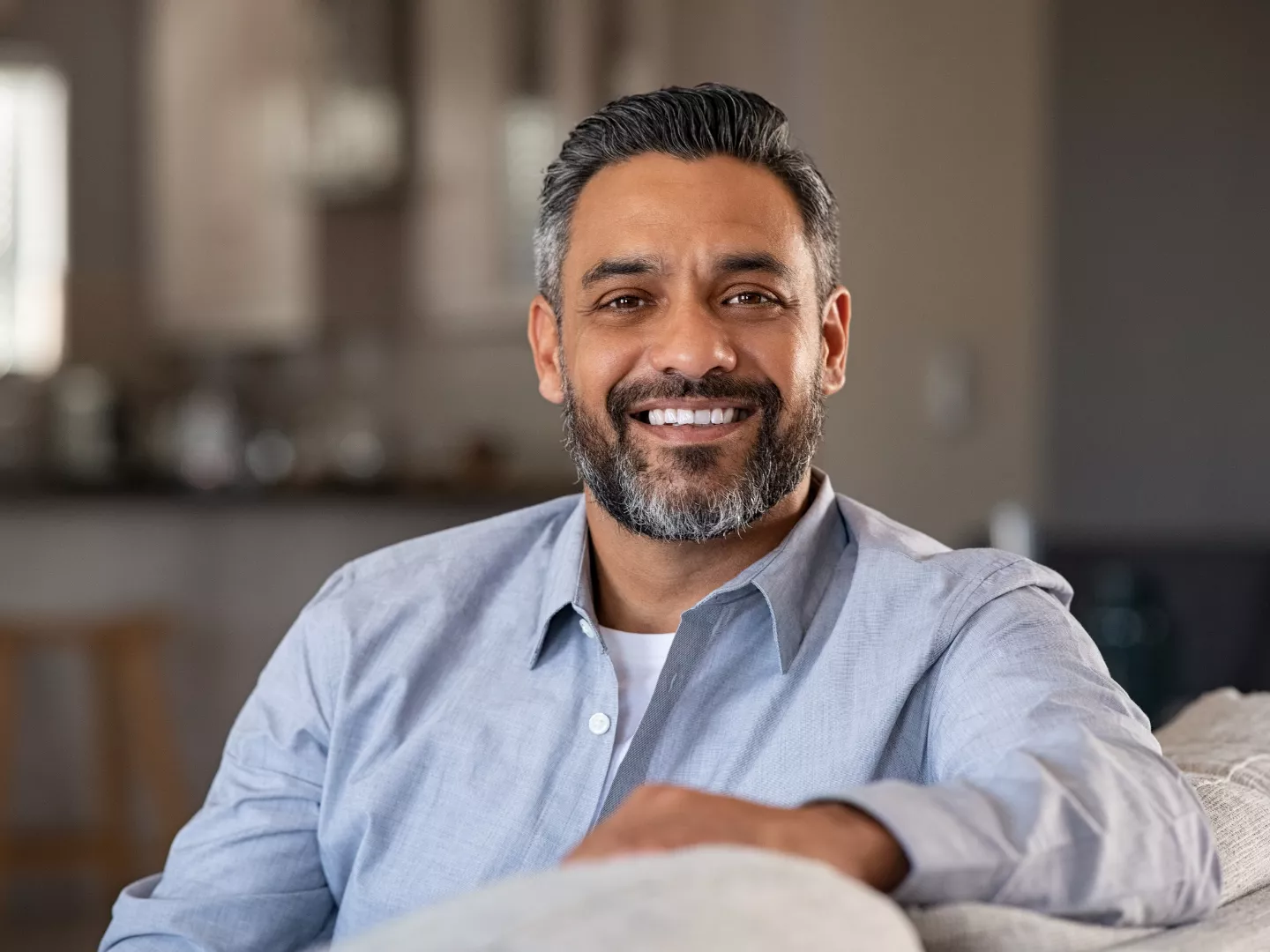 A smiling man at home comfortably with great teeth.